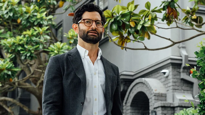 Dr. Block-Wheeler, wearing a blazer, descends a grand, carpeted staircase while holding a briefcase.