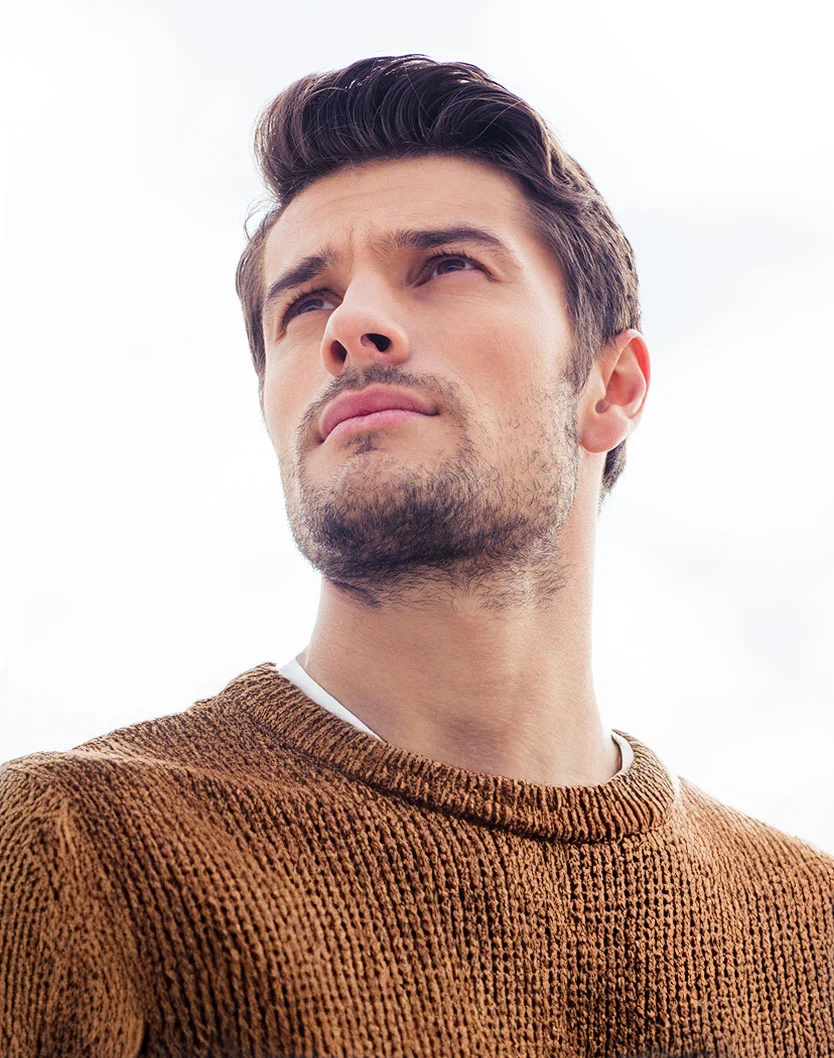 Close-up, low-angle shot of a handsome man in a brown sweater looking upward, highlighting his brow and forehead area. - Brow Lift in San Fransisco, CA
