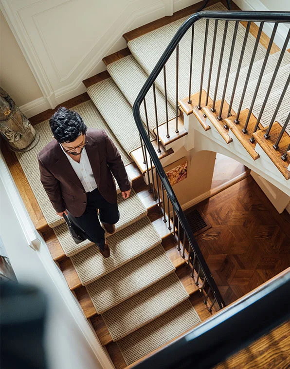 Dr. Block-Wheeler, wearing a blazer, descends a grand, carpeted staircase while holding a briefcase. - First Step in San Fransisco, CA